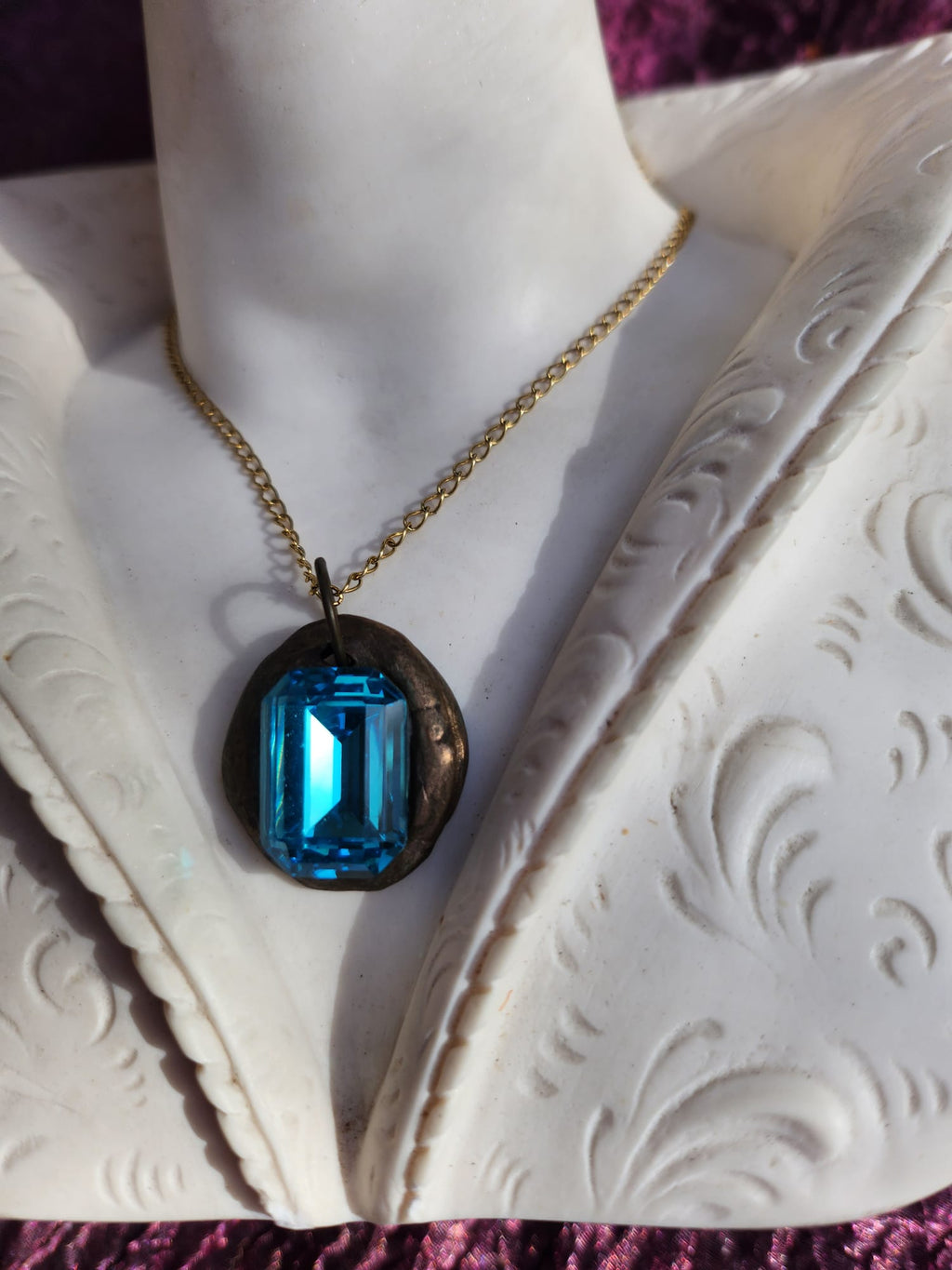 Colgante de bronce hecho a mano con cristal azul.