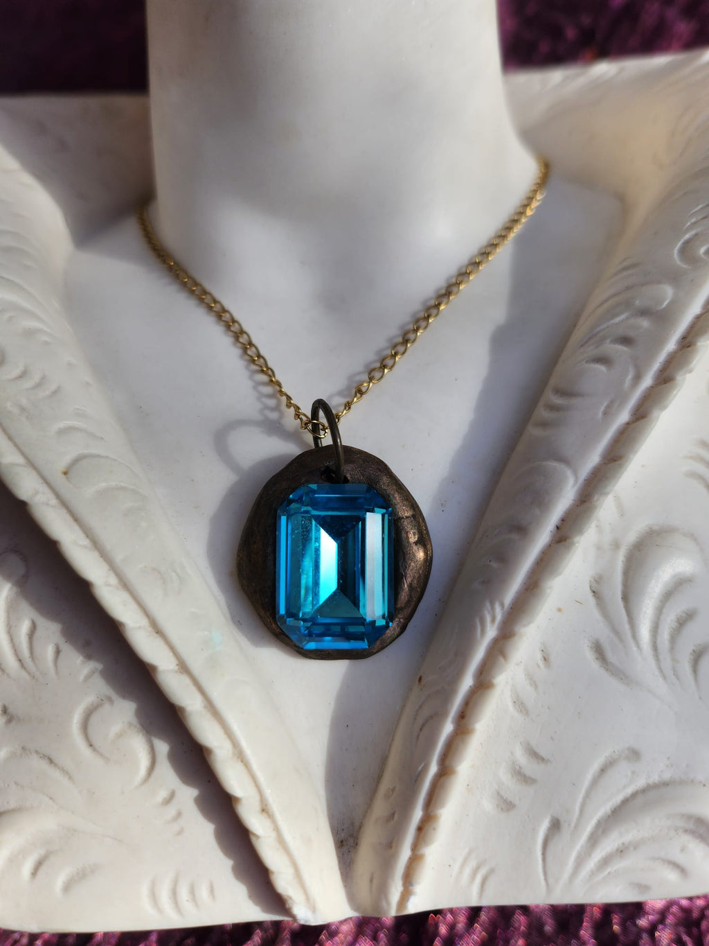 Colgante de bronce hecho a mano con cristal azul.