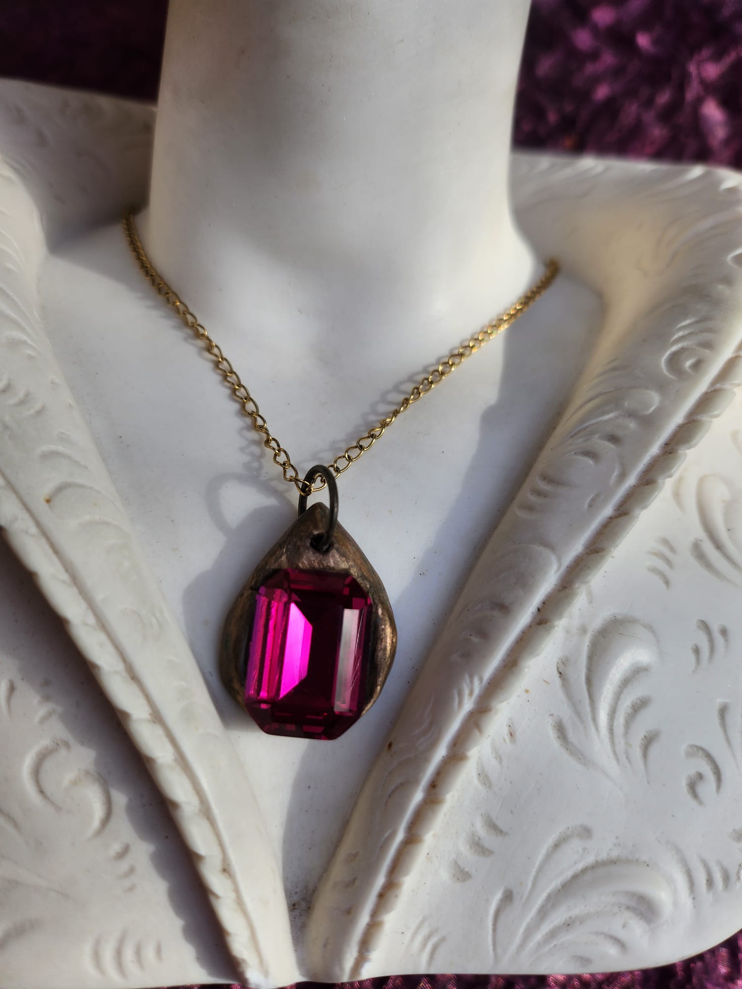 Colgante de bronce hecho a mano con cristal fucsia.