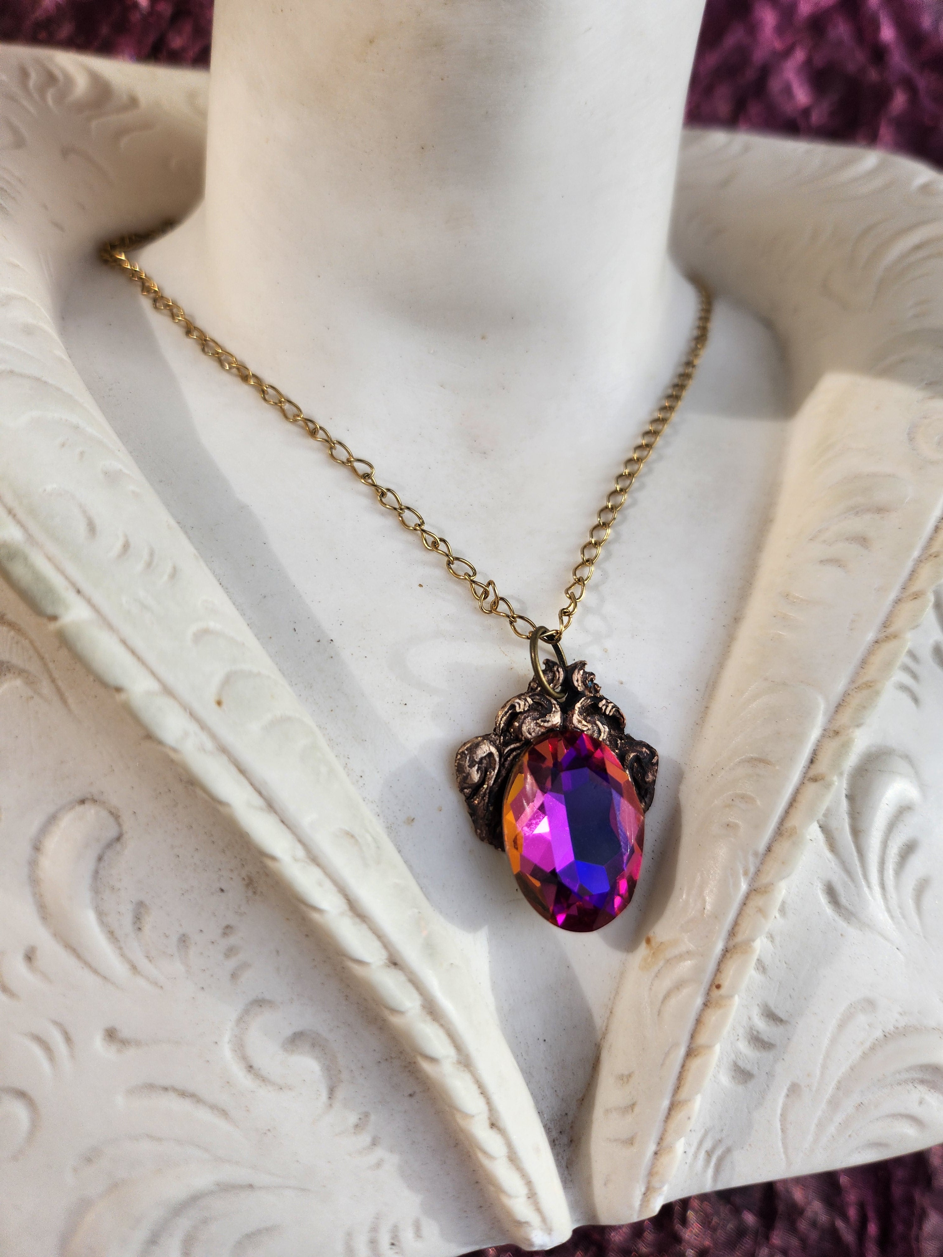 Coleção Ressonância Arcana – Pendente artesanal em bronze com cristal oval nas cores roxo, fúcsia e âmbar.