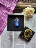 Coleção Barroca Mística – Pendente artesanal em bronze com cristal azul claro em forma de lágrima.